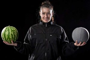 Une femme tient deux pastèques dont une recouverte d