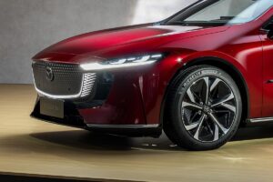 La nouvelle Mazda 6e électrique photographiée de trois-quarts avant, mettant en valeur sa silhouette élégante de berline et ses attributs distinctifs de version électrique.