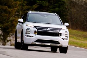 Mitsubishi Outlander PHEV nouvelle génération photographié sur route, montrant son design robuste, ses badges hybrides et sa prise de recharge visible