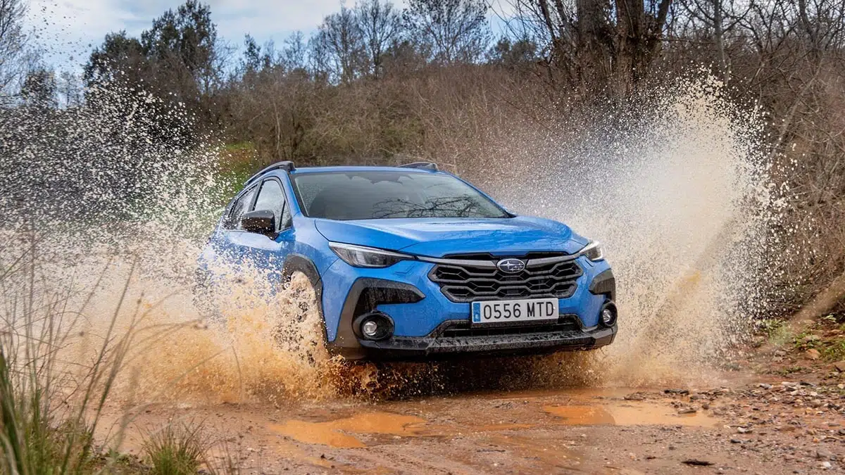 Cette incroyable petite voiture cache un 4x4 légendaire que vous ne pouvez pas manquer ! 4 Subaru Crosstrek 2025 vu de face franchissant un terrain boueux avec éclaboussures, démontrant ses capacités tout-terrain