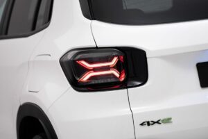 Le Jeep Avenger 4xe un 4x4 compact aux lignes robustes avec garde au sol élevée, protections de carrosserie visibles et jantes chaussées de pneus tout-terrain, présenté dans une teinte distinctive